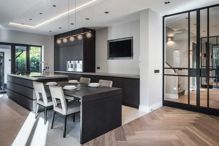 Keuken en leefruimte met donker kookeiland en stalen deuren