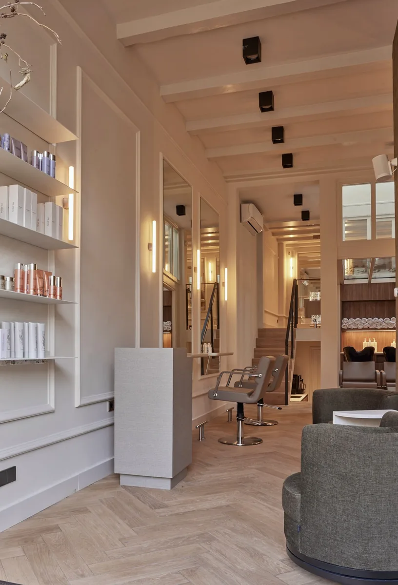 Salon met open schappen, spiegels en een ronde fauteuil