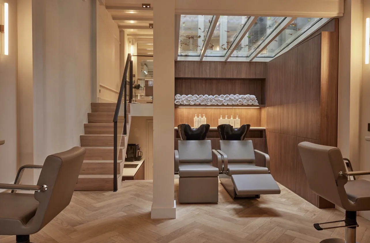 Salon met wasstoelen, houten wand en daglicht via het dakraam